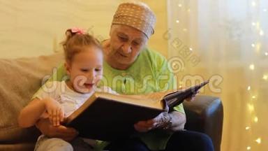 外婆和孙女一起读童话书.. 祖母拥抱她的孙女。